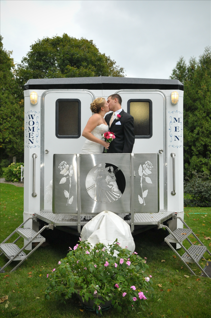 A bride and groom kissing in the back of their horse drawn carriage.